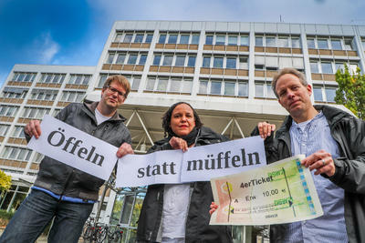 Drei Menschen halten das Ticket und den Slogan Öffeln statt Müffeln hoch